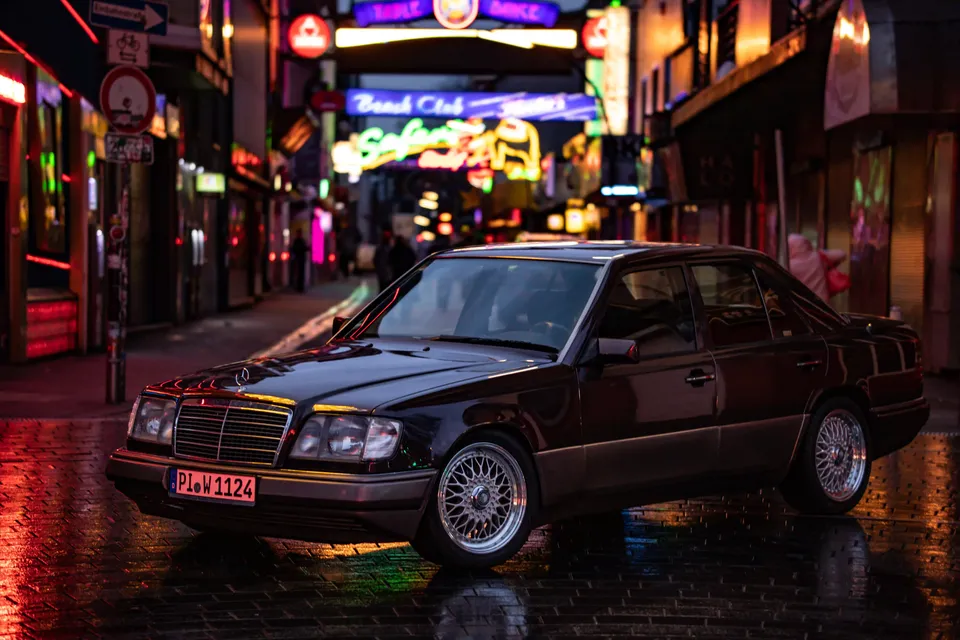 Mercedes vor bunt beleuchteten Fassaden bei Nacht
