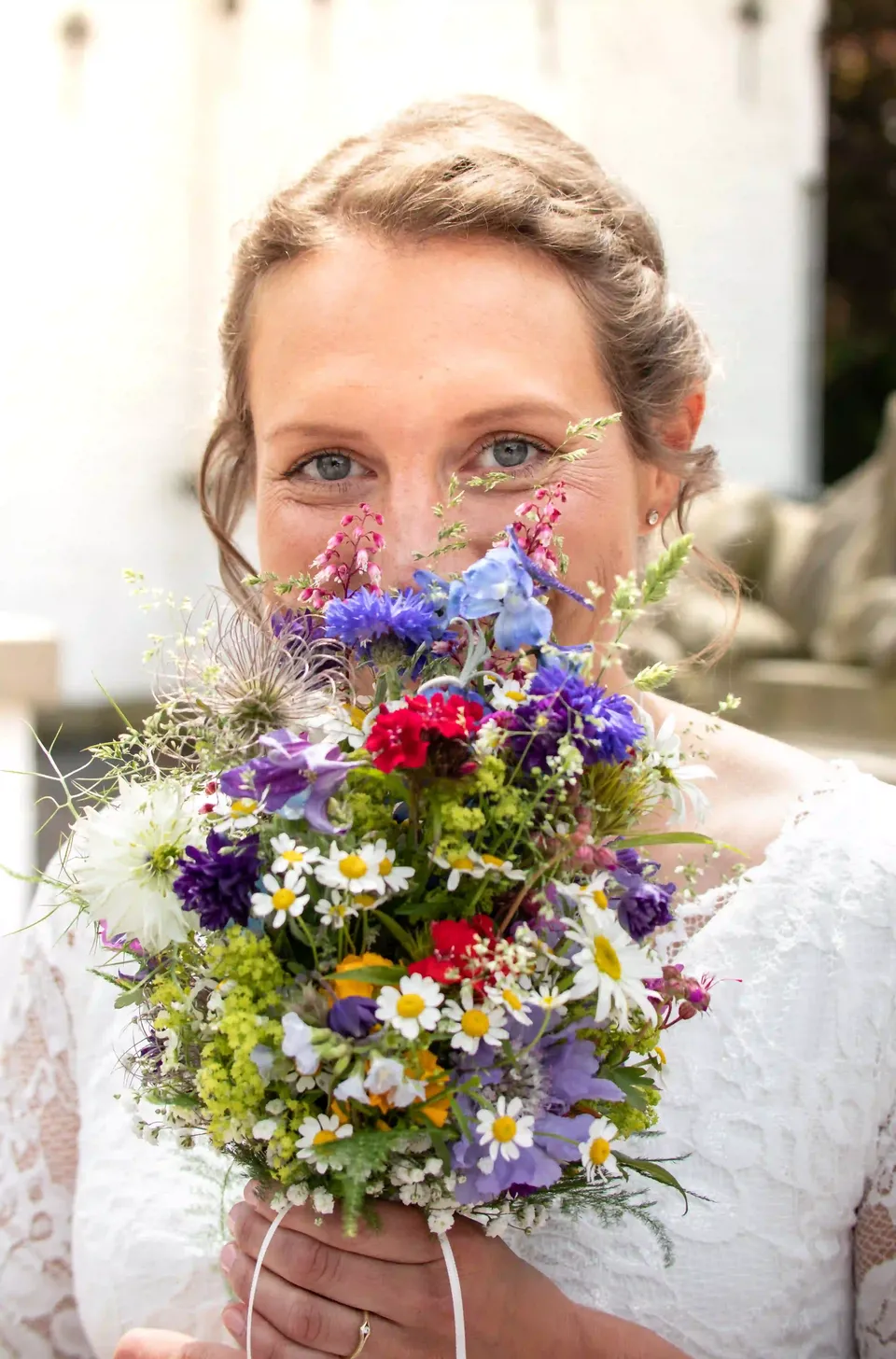Hochzeitsportrait einer Braut hinter einem bunten Blumenstrauß